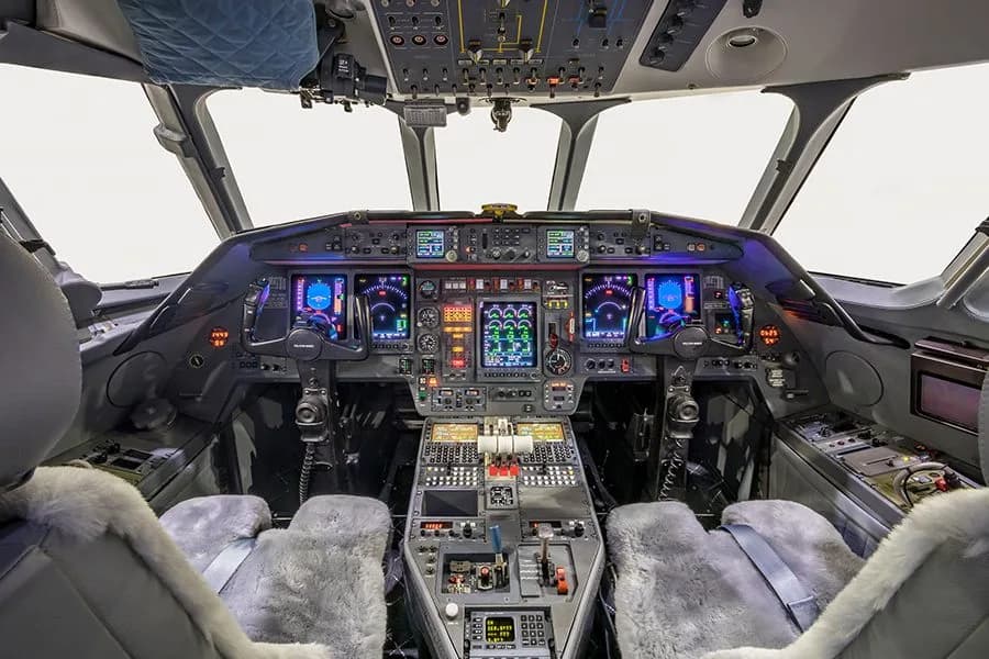 The illuminated cockpit of a private jet with multiple digital displays and controls.