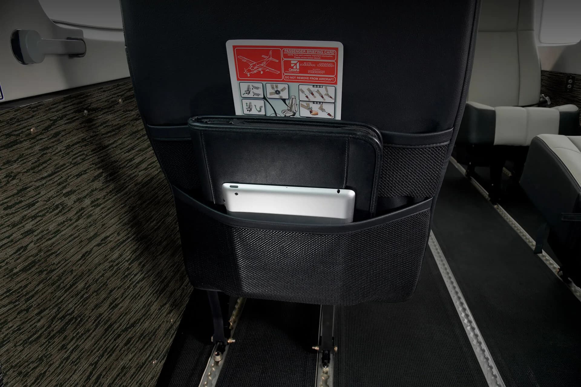 Seatback pocket with tablet and safety card in a Cessna Grand Caravan.