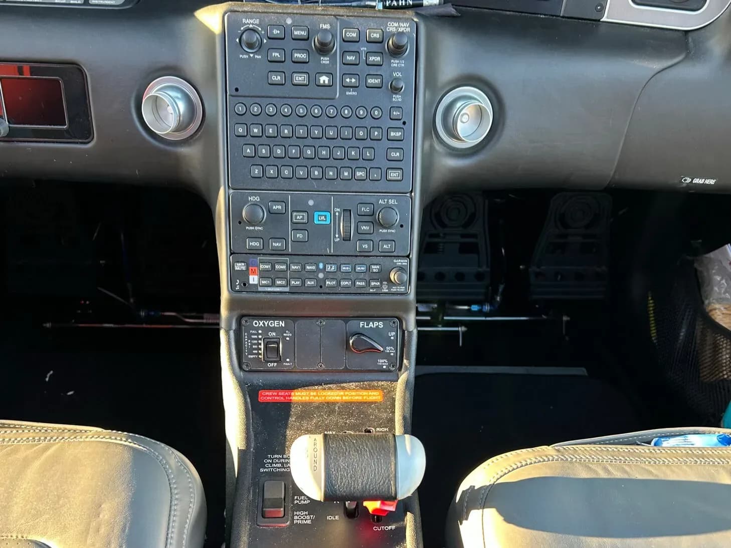 A close-up view of the central control panel in a Cirrus SR22 cockpit, showing buttons, switches, and throttle.