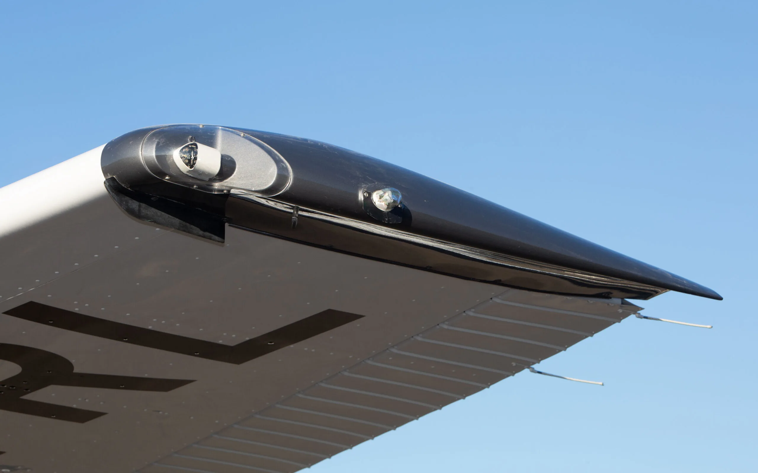 Close-up of the black wingtip of a Cessna 182T, showing navigation lights and part of the registration.