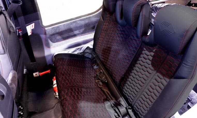 Rear seats of a Diamond DA62 aircraft with black leather and red stitching.