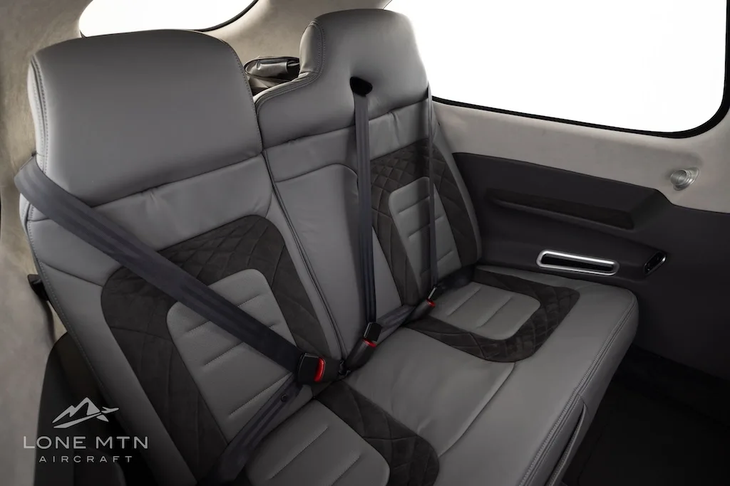 The gray and dark gray leather interior of the aircraft cabin, showing the rear seats with seatbelts.