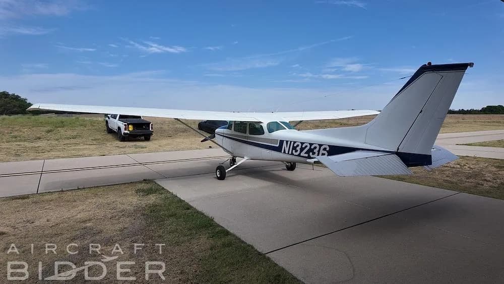 A rear-side view of a white and blue Cessna 172 Skyhawk (N13236) on a taxiway with a truck in the background.