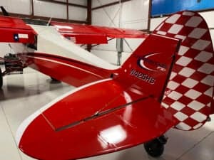 Close up of the tail of a red and white Cubcrafters FX-3 aircraft inside a hangar.