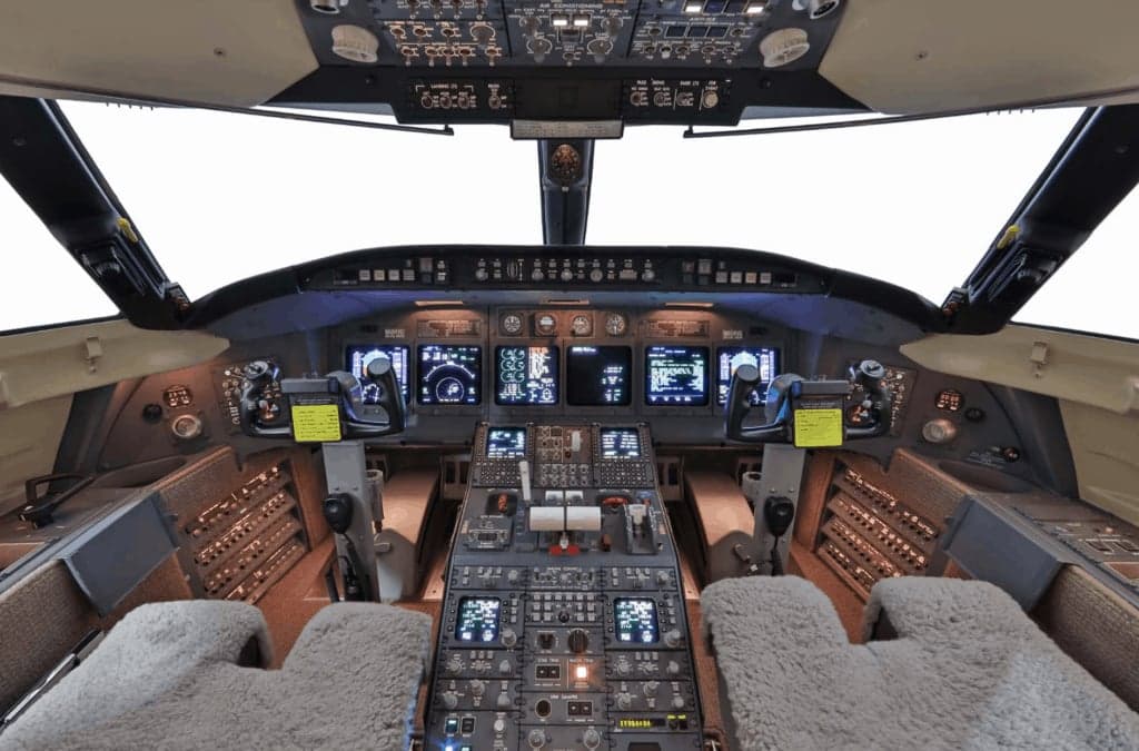 The cockpit of a business jet, featuring multiple digital displays and a complex control panel.