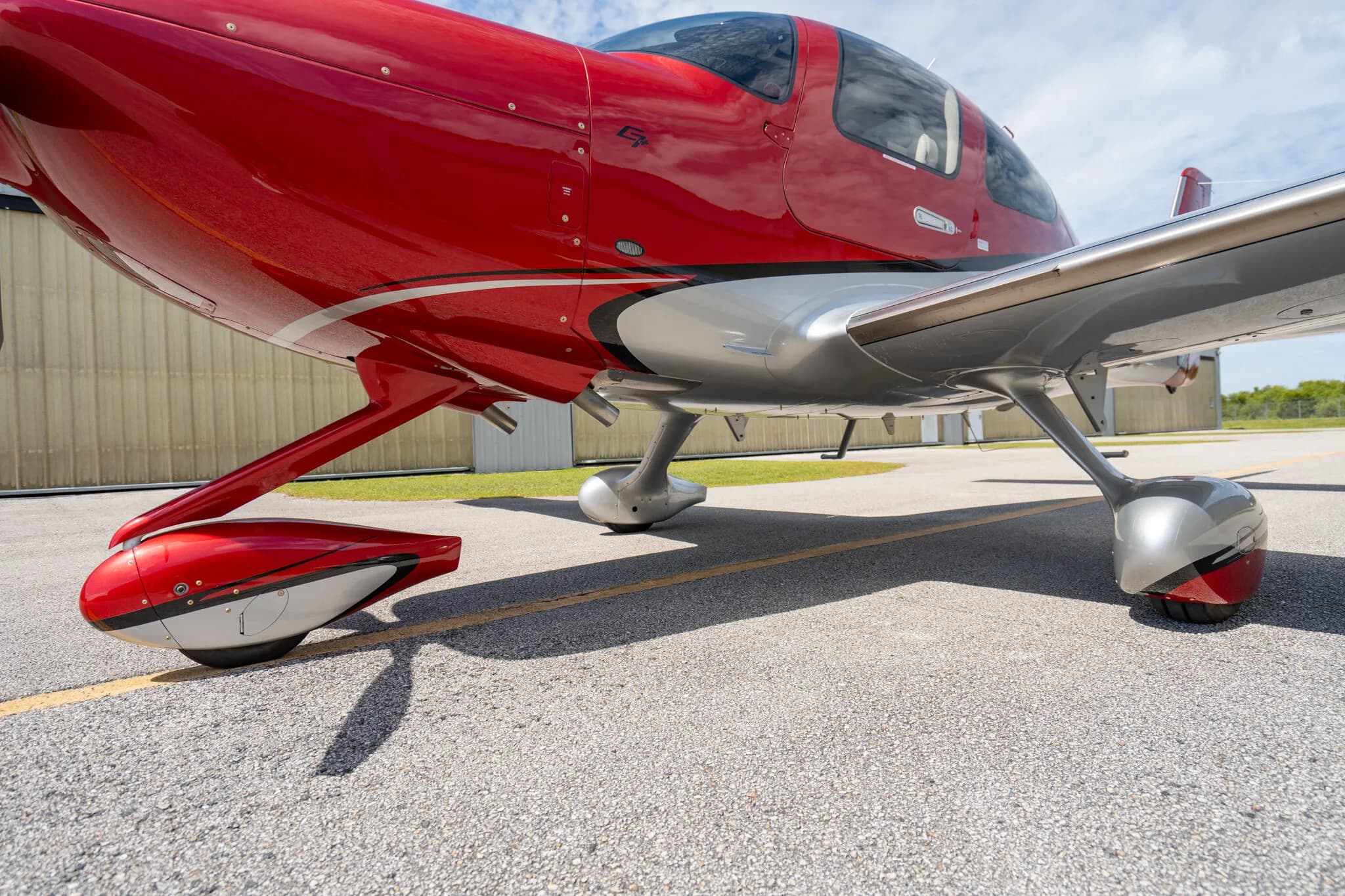 Close-up view of the landing gear and underside of the red and silver Cirrus SR22 GTS.