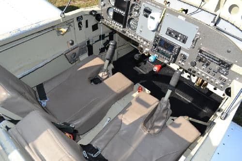 The interior of an aircraft cockpit is shown with seats and controls.