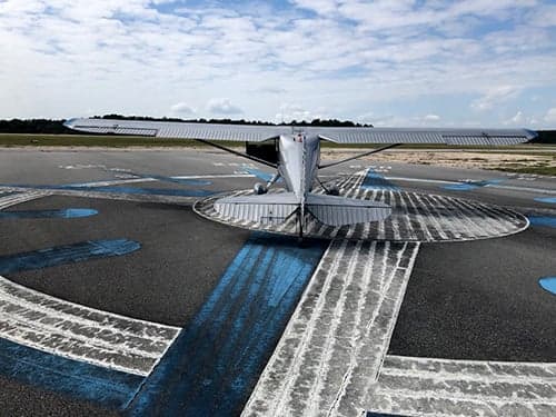 Front view of a silver and blue aircraft on a tarmac.