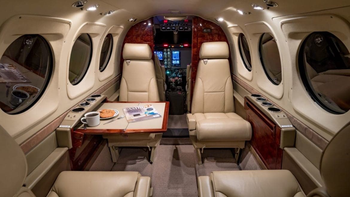 Interior view of the aircraft cabin with a table, seats, and cockpit visible.