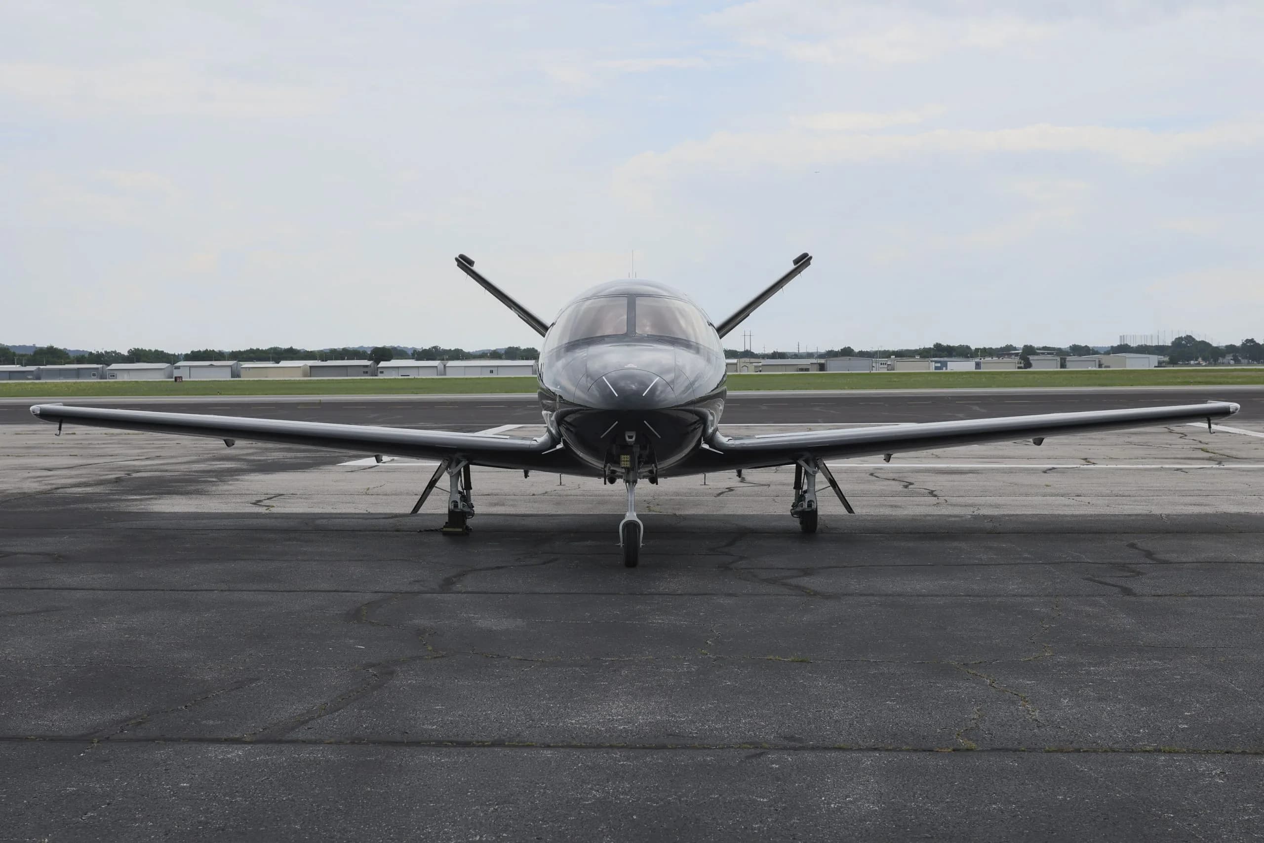 A black Cirrus Vision Jet (N25KQ) is seen from the front, parked on an airport tarmac.
