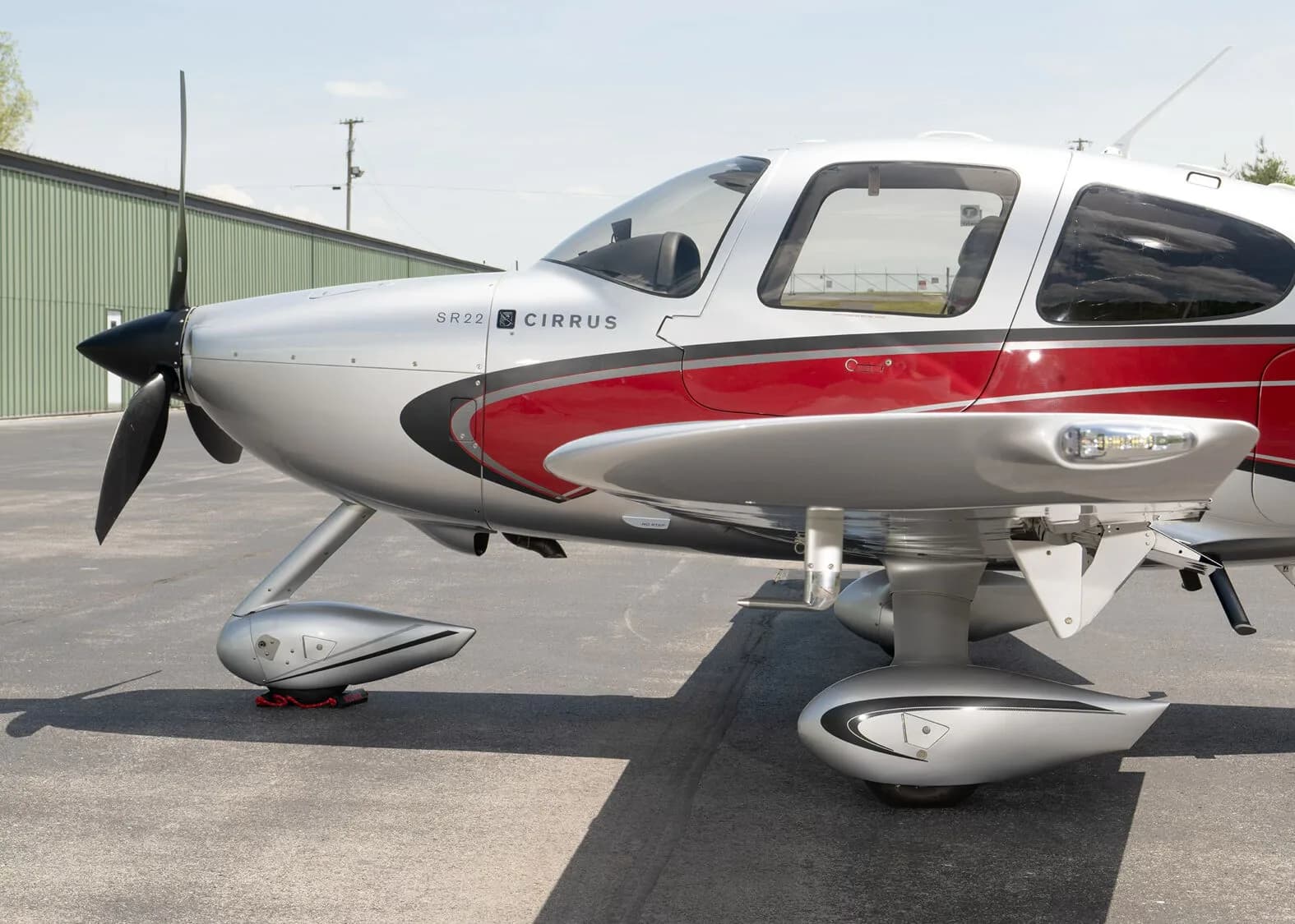 A close-up side view of the front section of a silver and red Cirrus SR22 aircraft, N224KR, showing the propeller and landing gear.