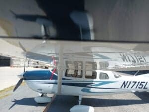 Side view of a Cessna aircraft with blue and white paint scheme, parked on the tarmac with the tail number N1715L visible.