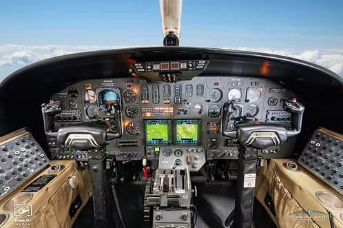 The cockpit of a business jet features a complex instrument panel with multiple screens and controls.