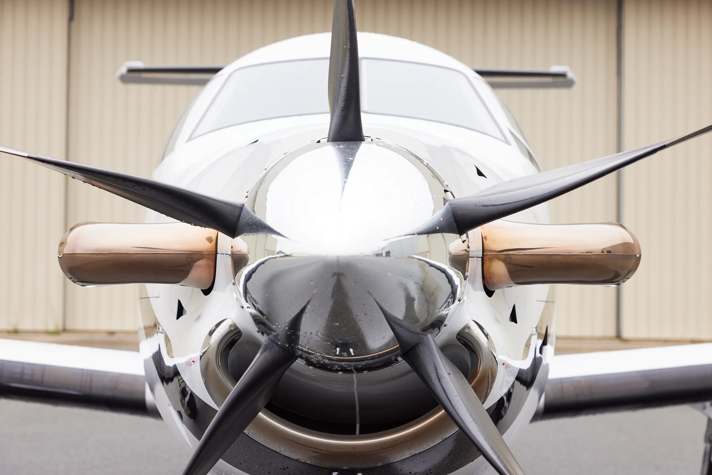 A close-up front view of a Pilatus PC-12 aircraft, highlighting its propeller and nose.