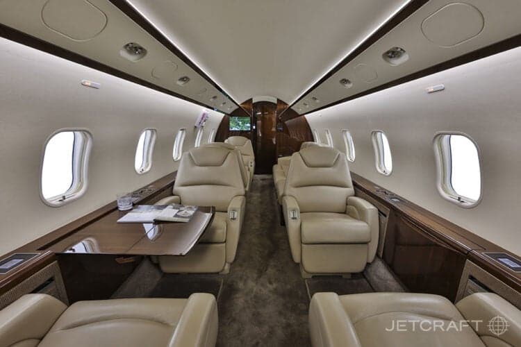 View of the aircraft cabin with leather seats and a table with a magazine.