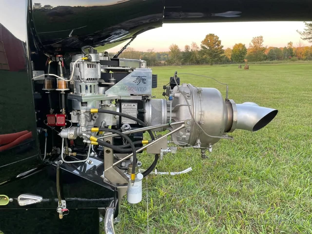 A detailed view of the exposed turbine engine of the black helicopter, showing its components and plumbing.