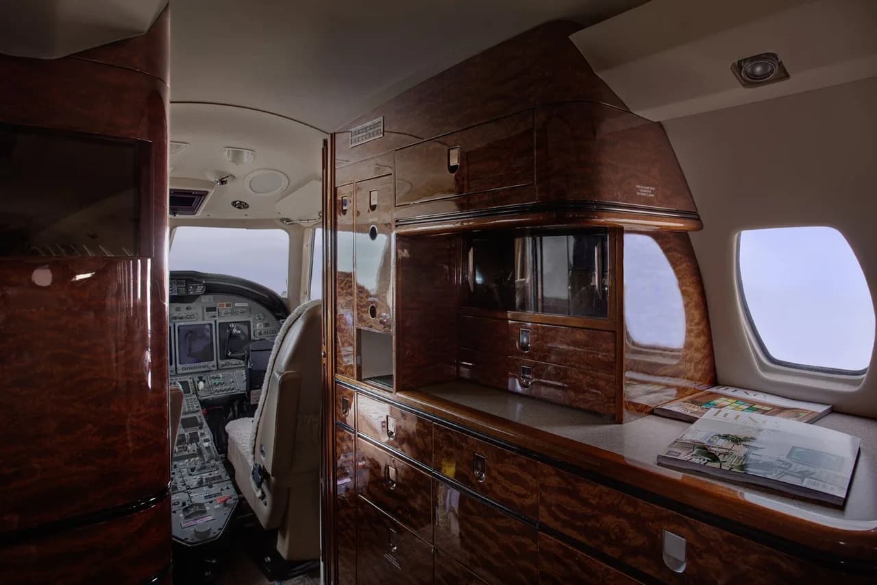 Aircraft interior with wood cabinetry and a view of the cockpit.
