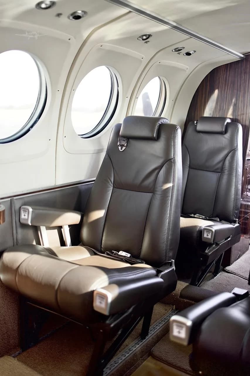 A close-up view of two dark leather passenger seats in the aircraft's cabin, next to a window.