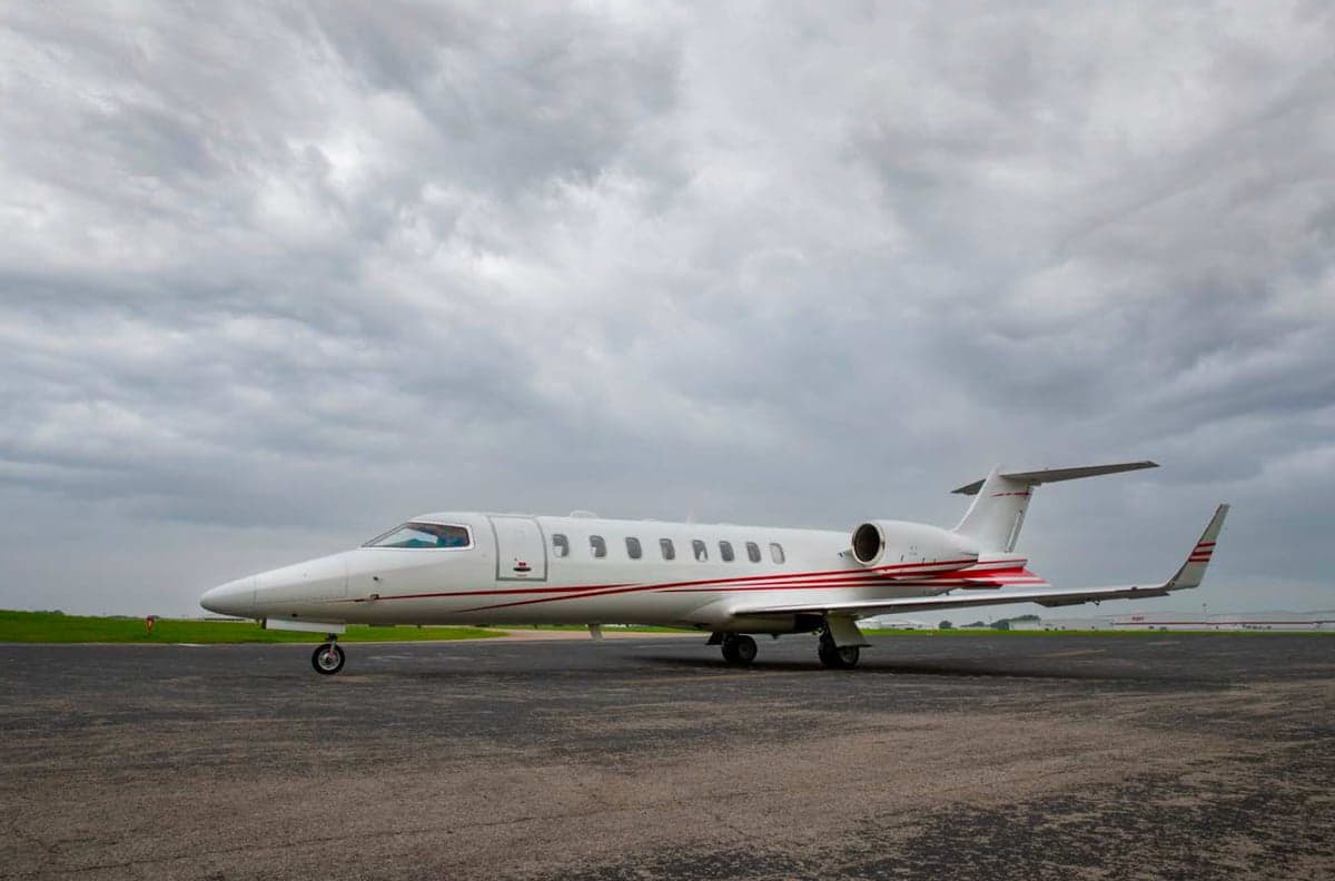 A Learjet aircraft is parked on the tarmac under a cloudy sky.