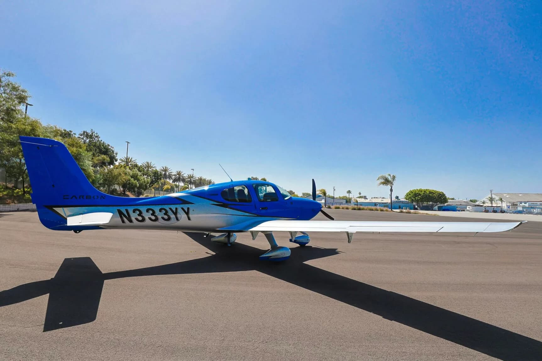A three-quarter rear view of the blue and silver Cirrus SR20 aircraft N333YY parked on an asphalt ramp.