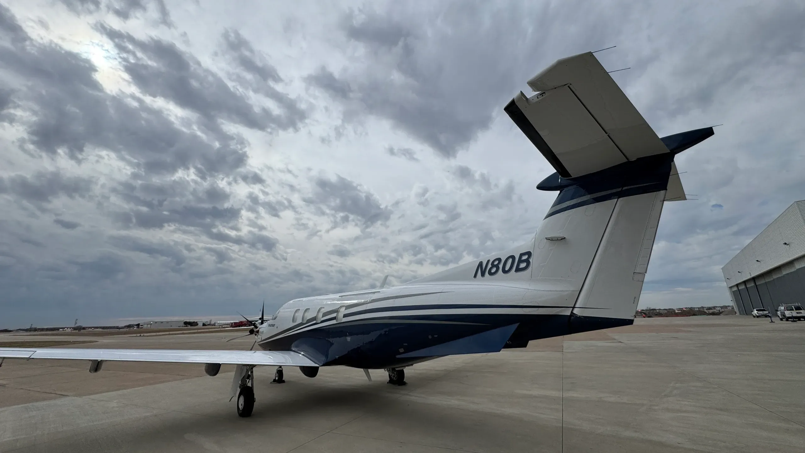 The spacious interior cabin of a private jet, featuring light grey quilted seats and overhead lighting.
