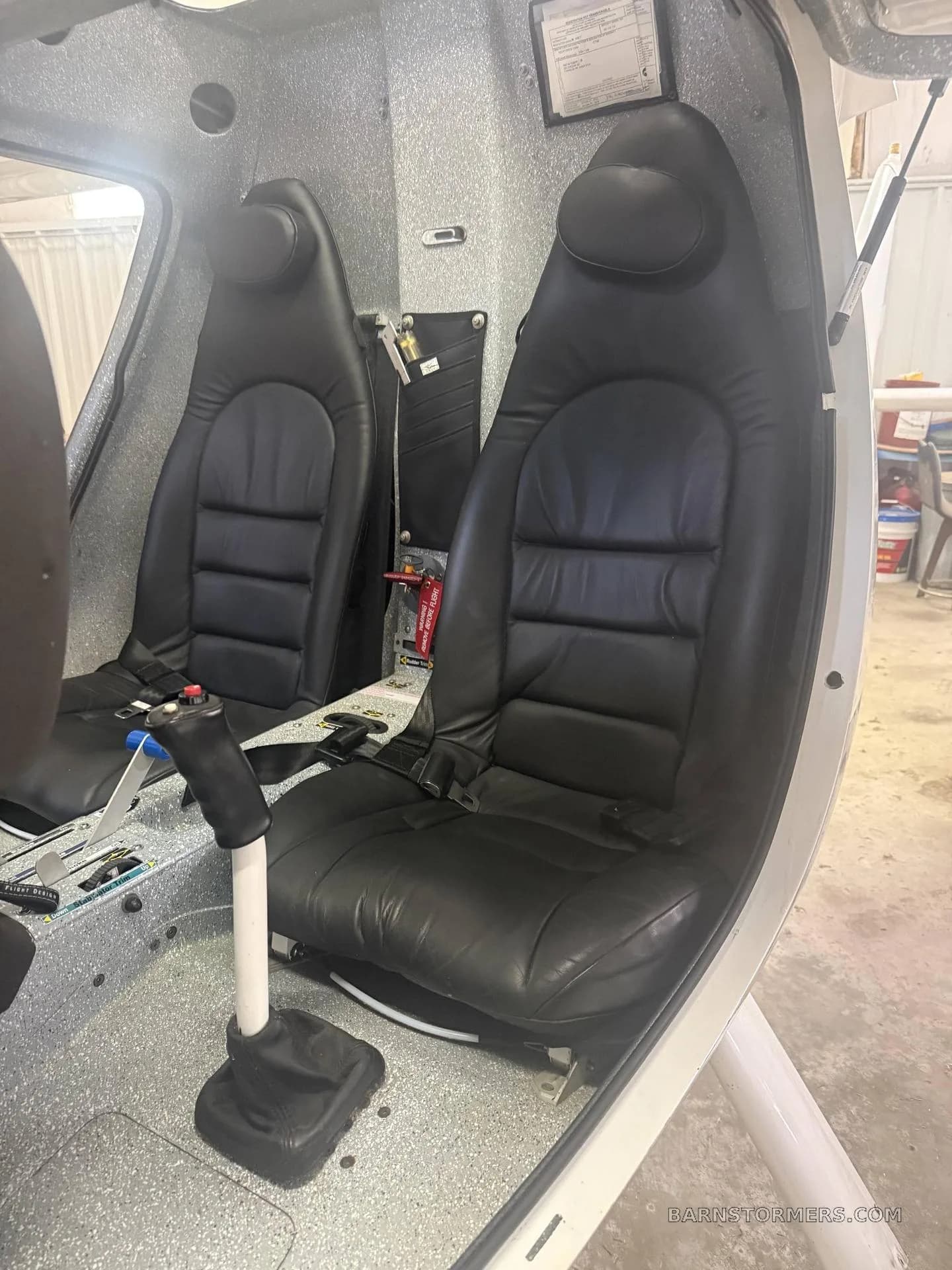 The interior of a Flight Design CTLS aircraft, featuring two black leather seats and a center stick control.