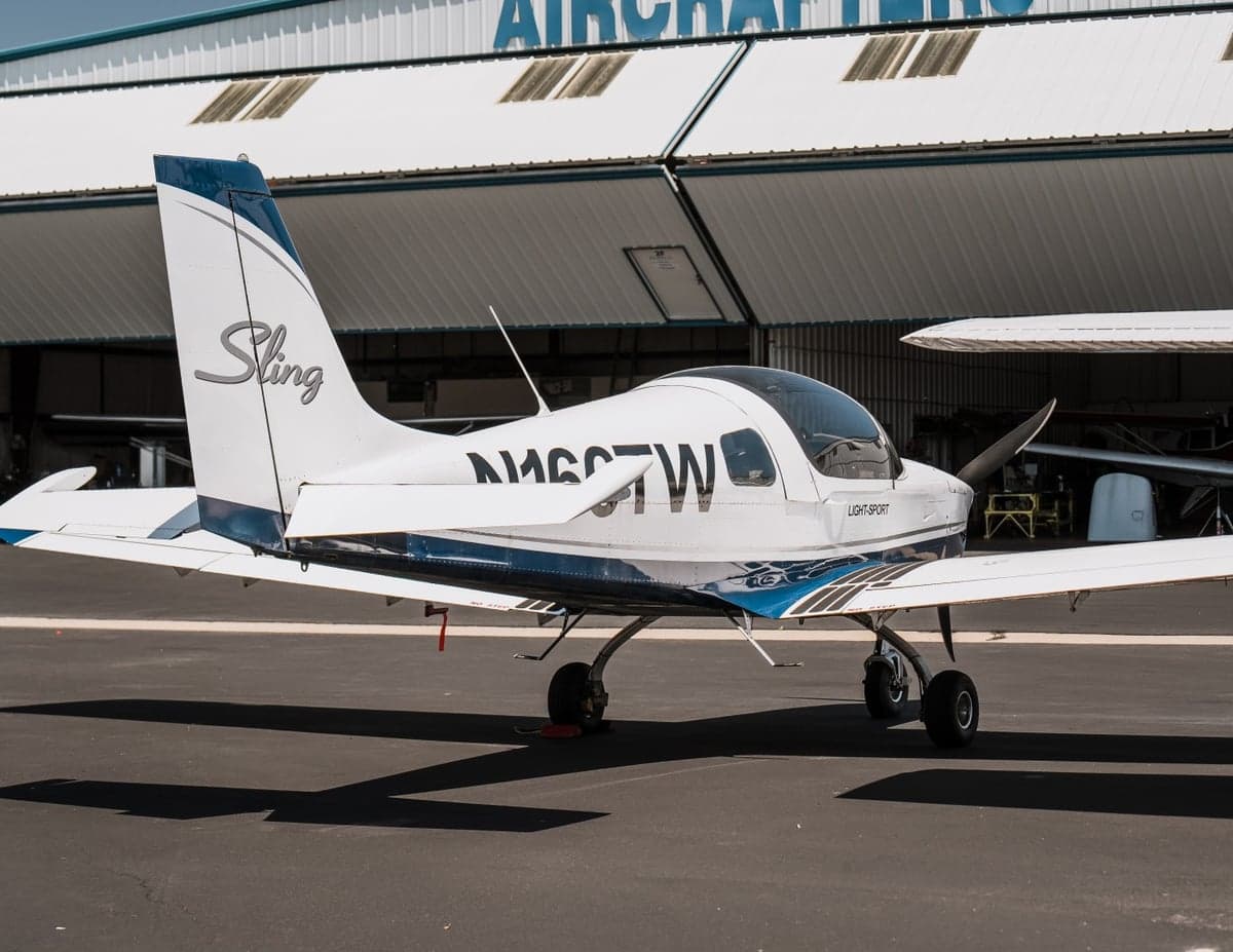 Side view of the Sling LSA aircraft parked in front of a hangar.