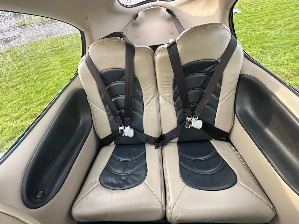 An overhead view of the tan and black leather rear seats inside the Cirrus SR22 cabin with seatbelts fastened.