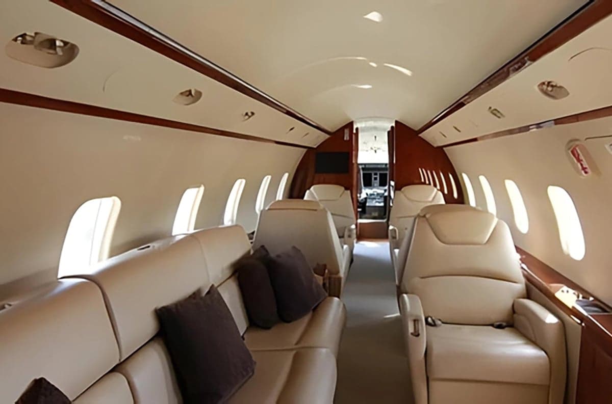 View of the aircraft interior with tan leather seats and dark brown pillows.