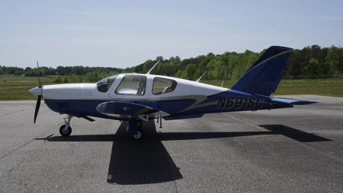 A side view of a white and blue single-engine aircraft with N691SC registration on the tail.
