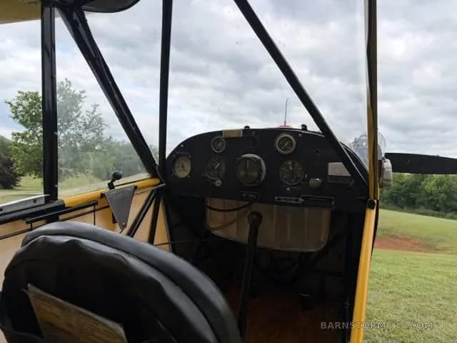The simple instrument panel and controls of a yellow aircraft, viewed from the pilot's seat.