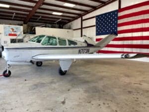 Side view of a Beechcraft Bonanza aircraft with registration N7173N in a hangar.