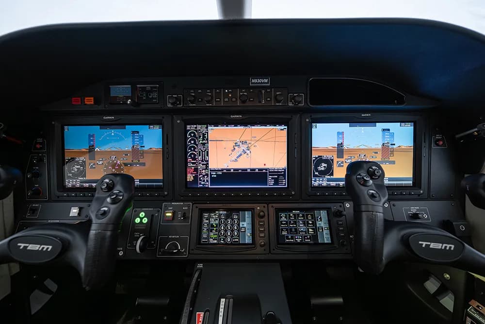 Close-up view of the aircraft cockpit with multiple Garmin displays and control yokes.