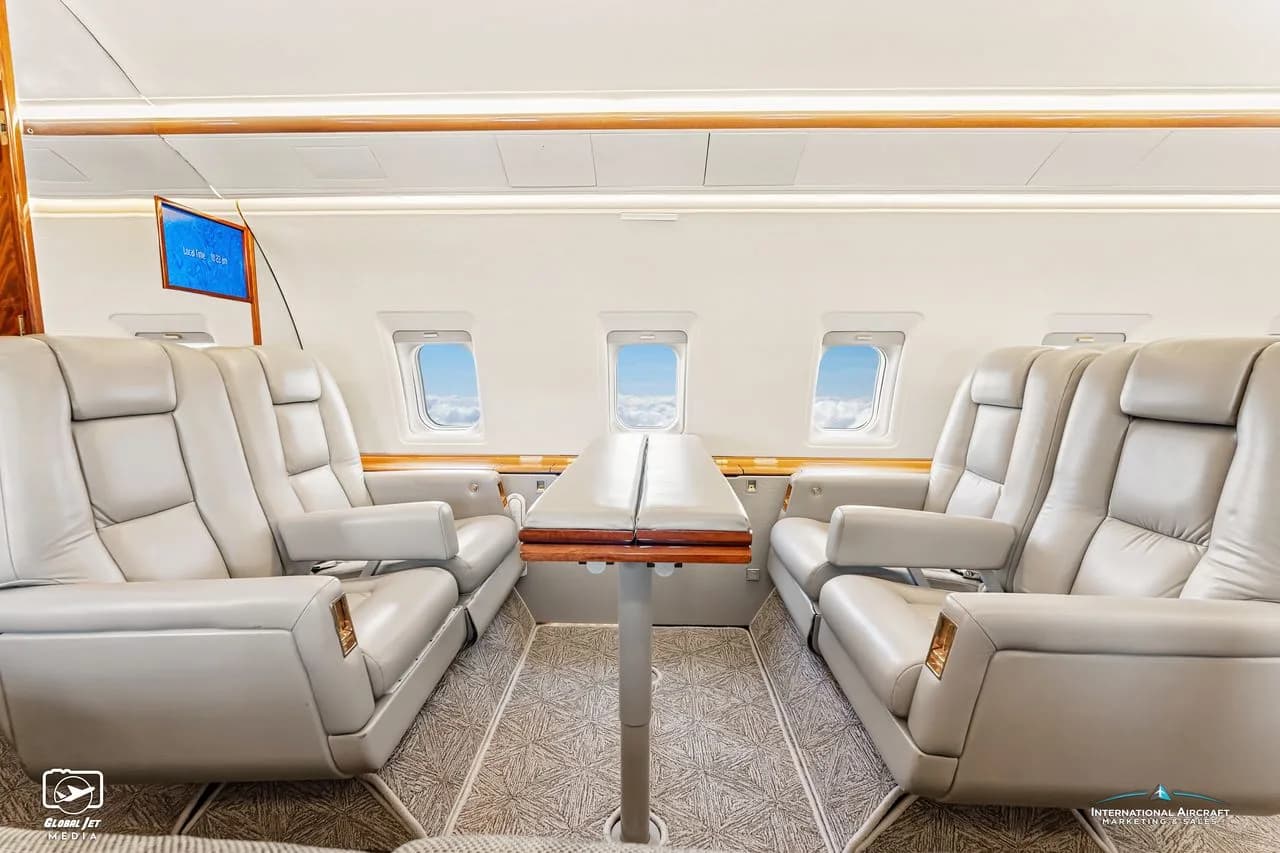 Interior view of the aircraft cabin with leather seats and a folding table.