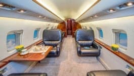 View of the Challenger aircraft interior with a leather seat and table setting.