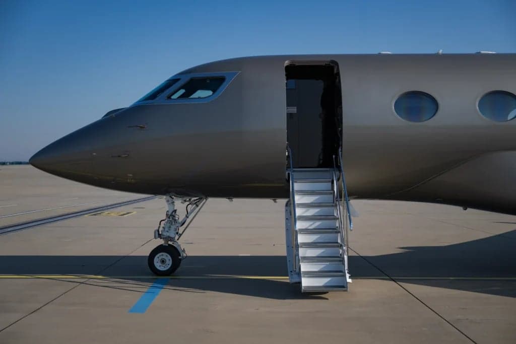 Close-up of the nose and open entry door of a gray Gulfstream jet.