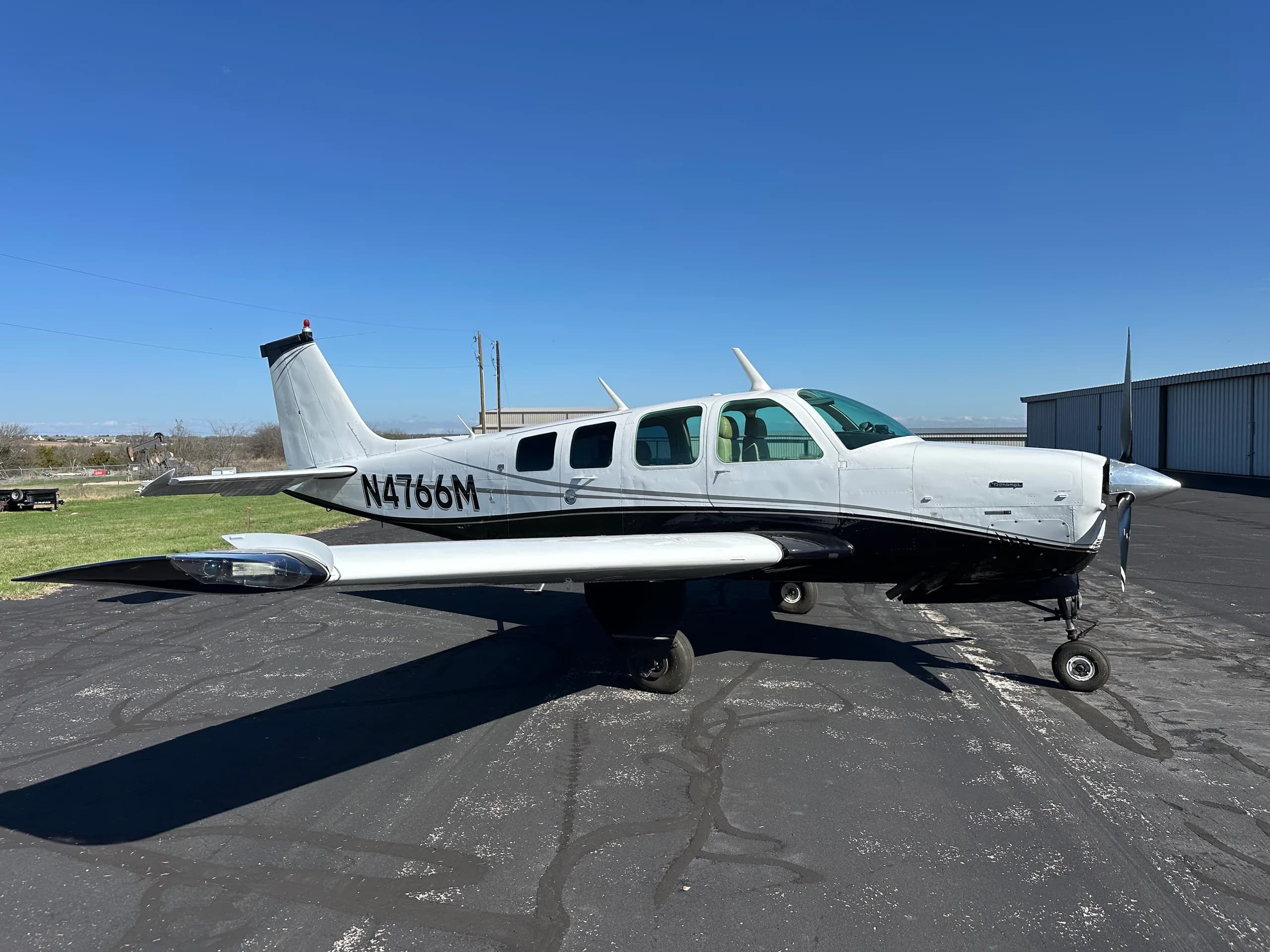 A Beechcraft Bonanza aircraft with registration N4766M is parked on the tarmac.