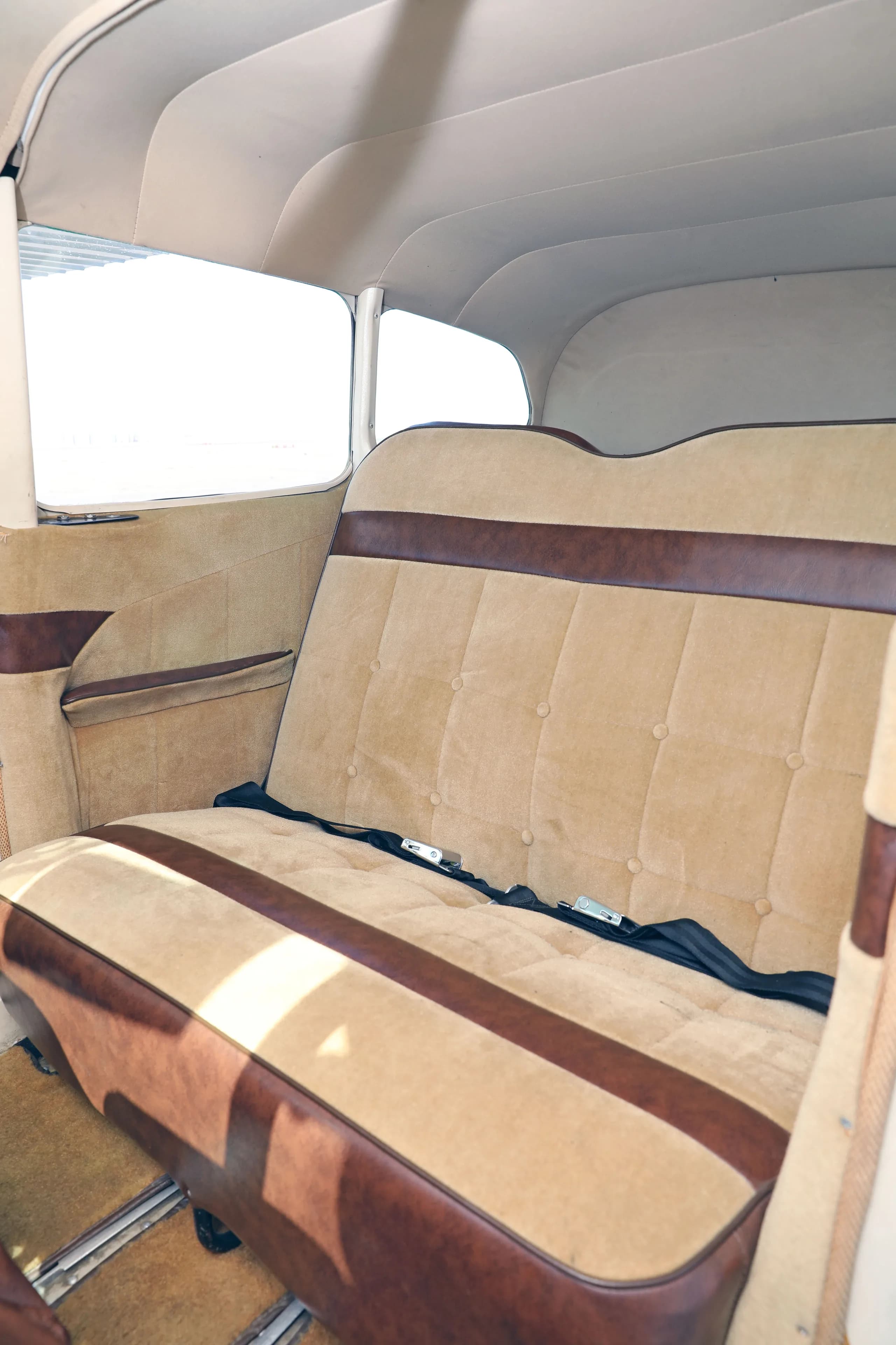 A close-up view of the tan and brown rear bench seat in the cabin of a Cessna 182 Skylane.