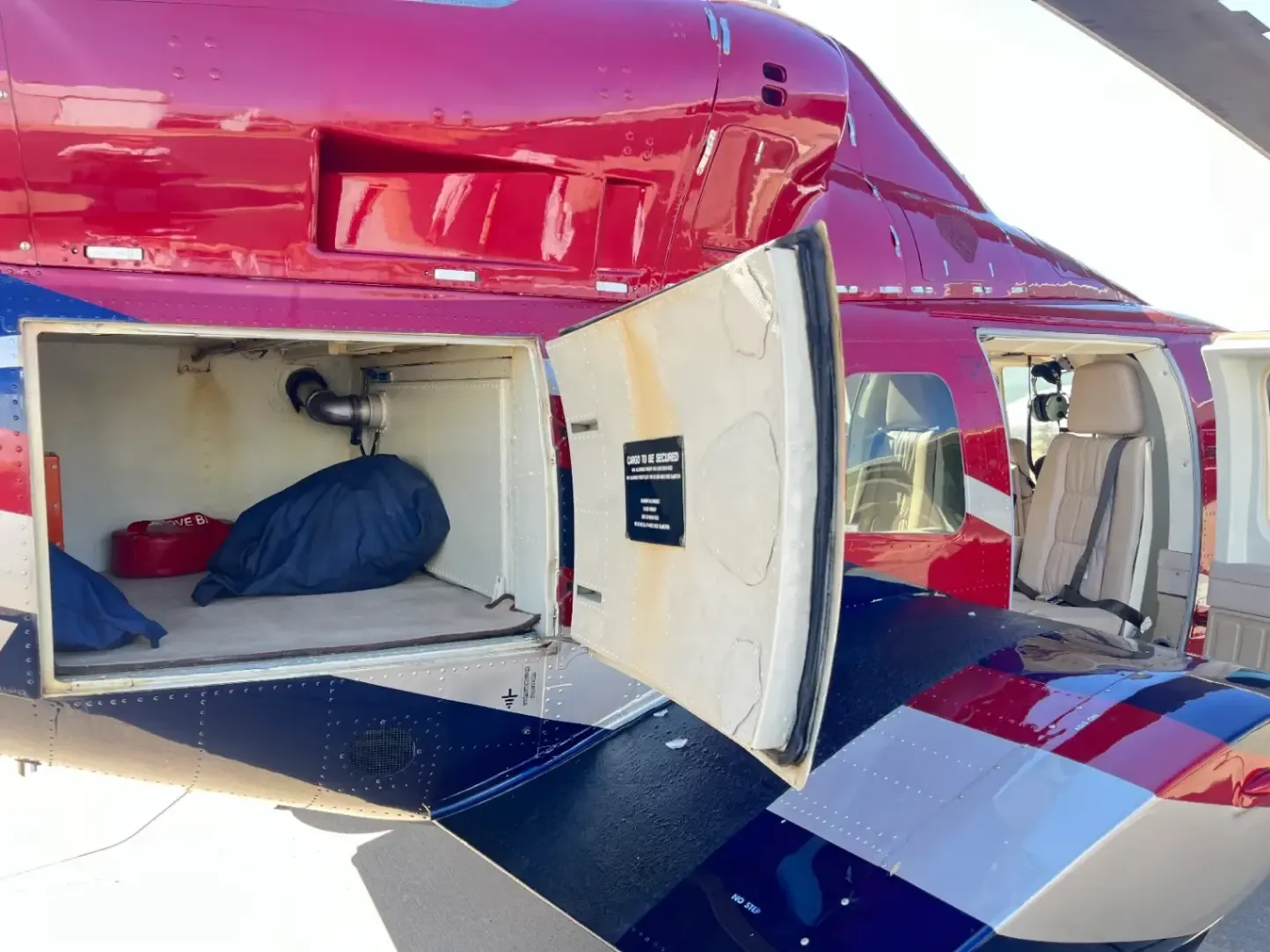 The open cargo compartment of the helicopter shows storage bags and a cockpit voice recorder.