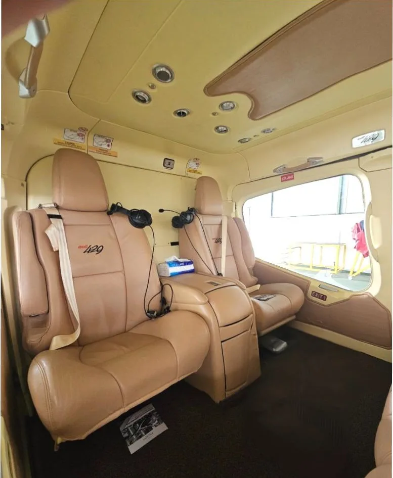Interior view of the helicopter cabin with tan leather seats and headsets.