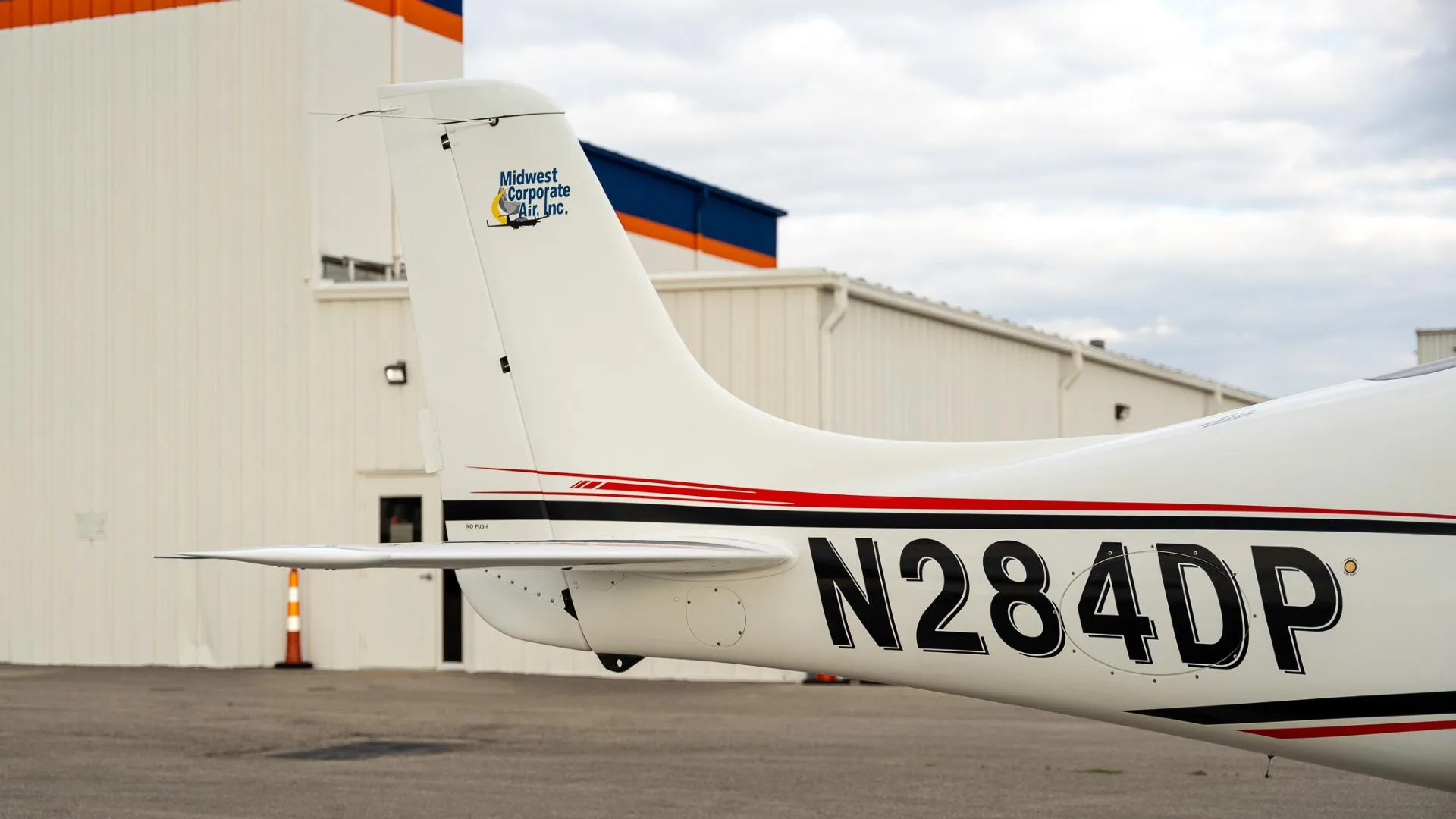 A close-up of the tail section of the white Cirrus SR22 aircraft, showing the N284DP registration and "Midwest Corporate Air, Inc." logo.