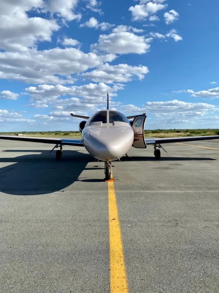 Front view of A2-PGC Cessna Citation Mustang on the tarmac with the door open.