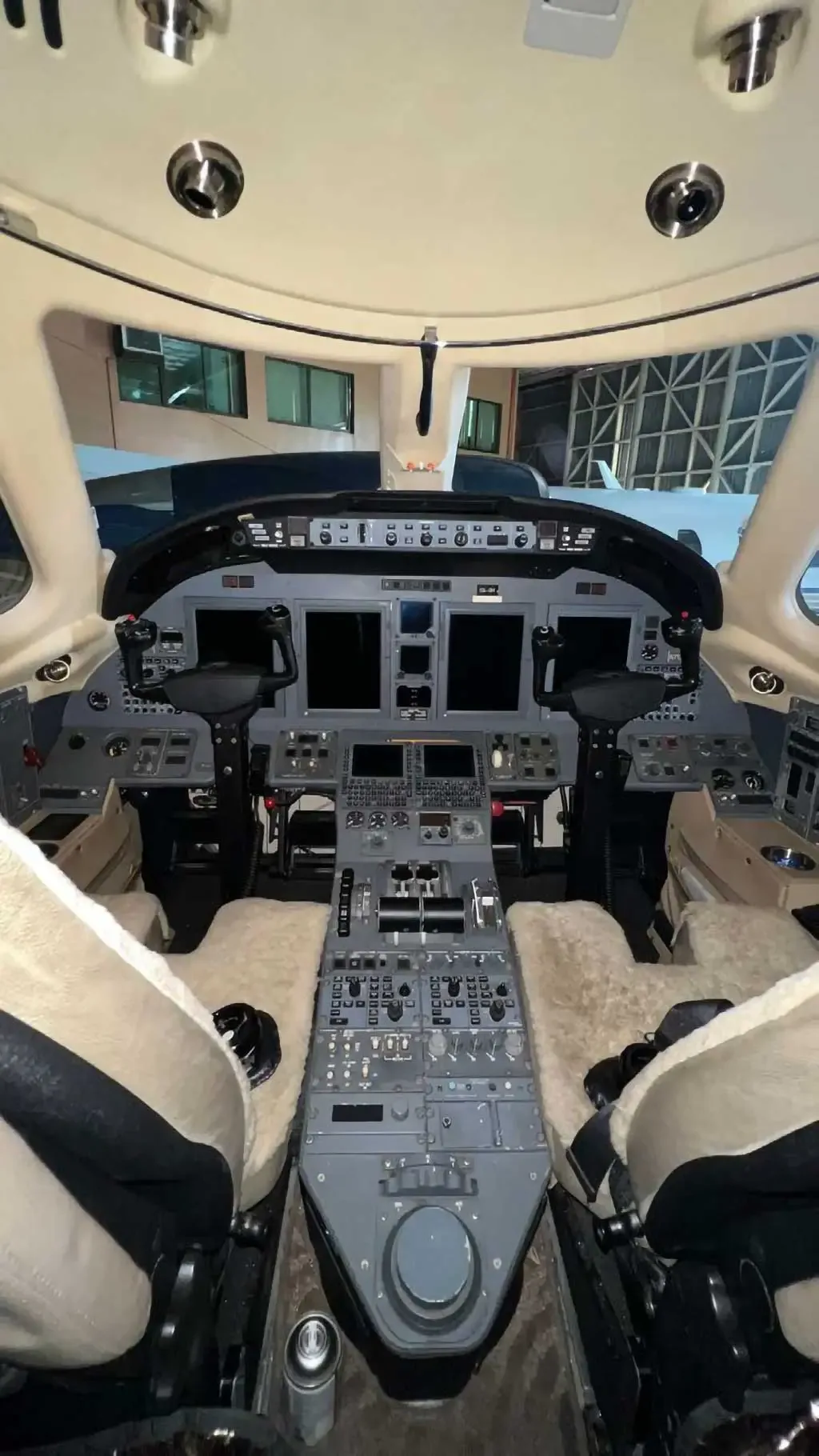 The aircraft cockpit with a modern glass panel display, multiple controls, and two pilot seats.