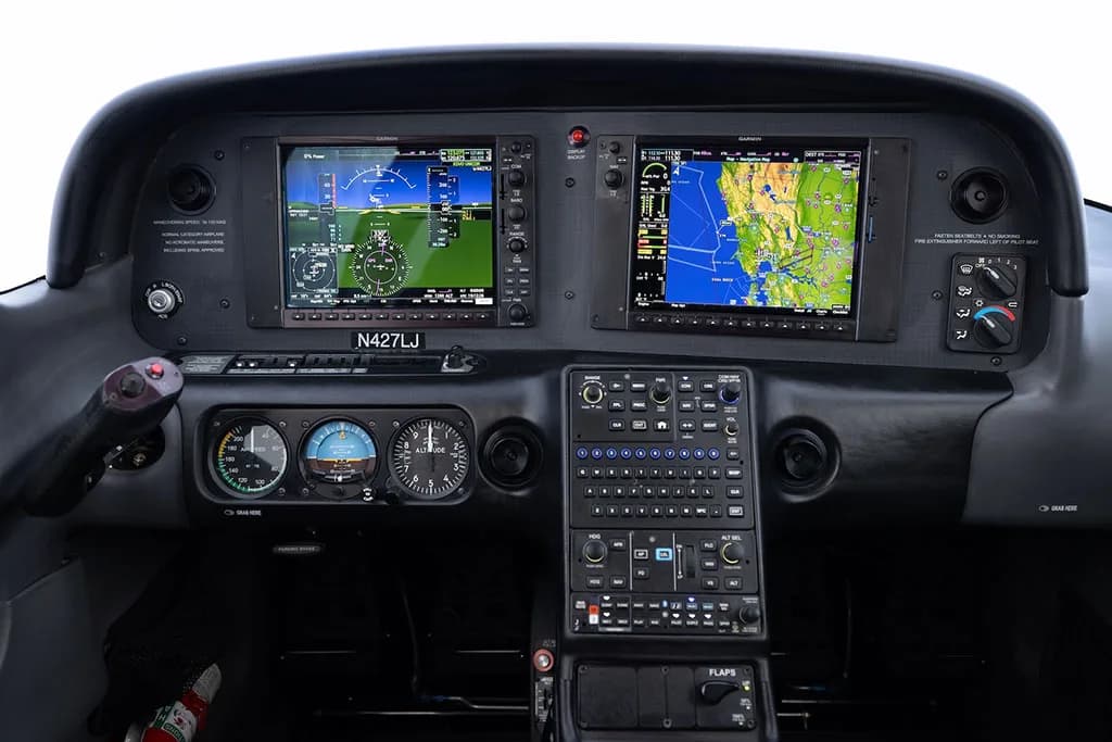 Close-up view of the aircraft's instrument panel with dual Garmin displays and various controls.