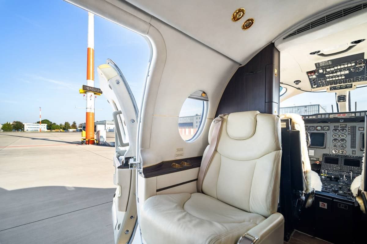 Interior view of the Beechcraft Beechjet 400A cabin showing a seat and the cockpit with the door open.