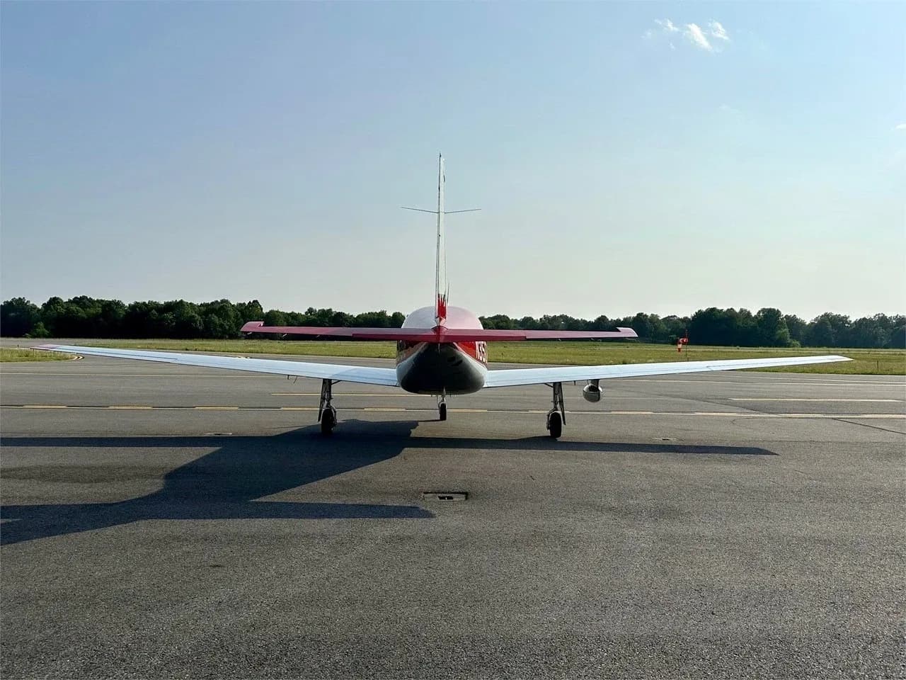 A rear view of the red and silver Piper M350 aircraft parked on an airport tarmac.