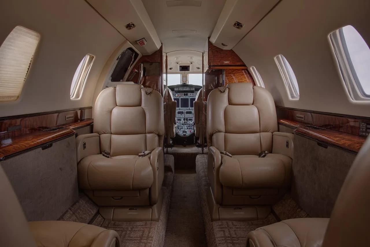 Aircraft interior with leather seats and a view of the cockpit.