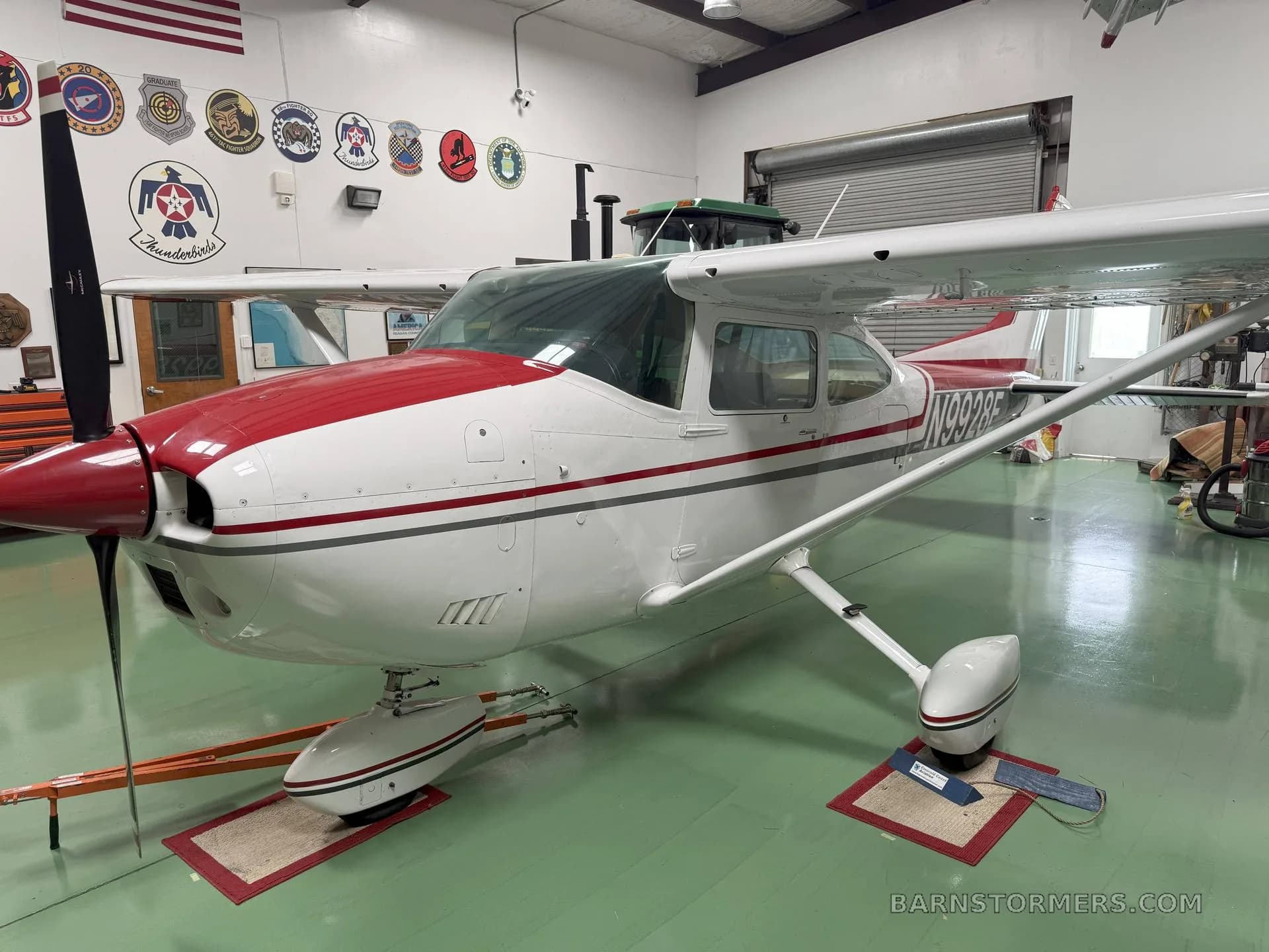 A white and red single-engine propeller aircraft, N989BE, is parked inside a hangar.