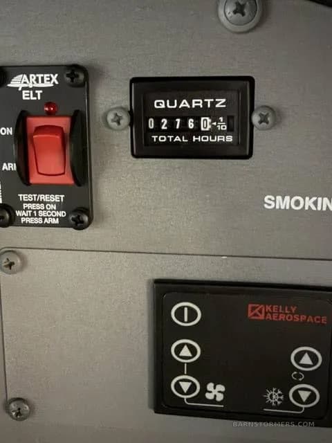 A close-up view of an aircraft's hour meter showing 276.0 total hours, next to an ELT switch.