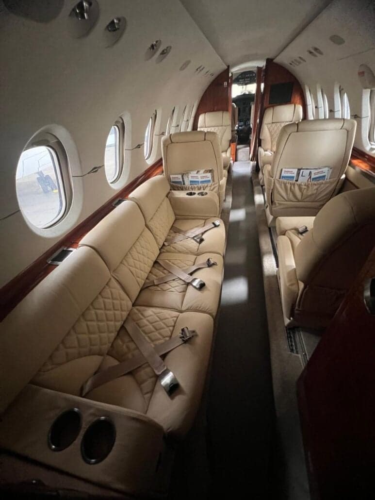 View down the aisle of the aircraft's cabin with tan leather seats.